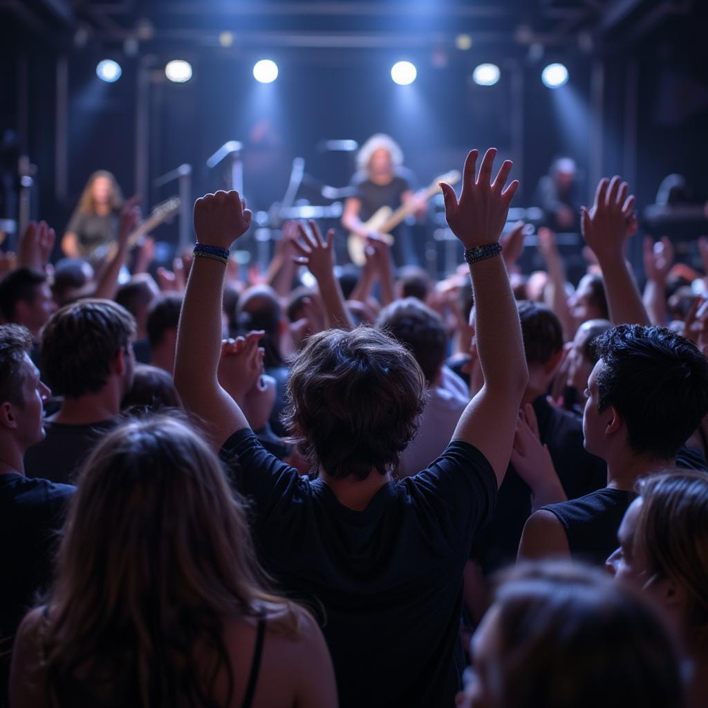 A diverse crowd at a pop rock concert with their hands raised in the air