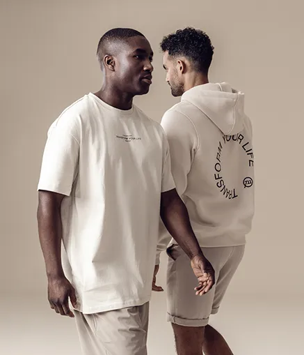 2 junge Männer laufen nebeneinander vorbei in Streetwear Klamotten.