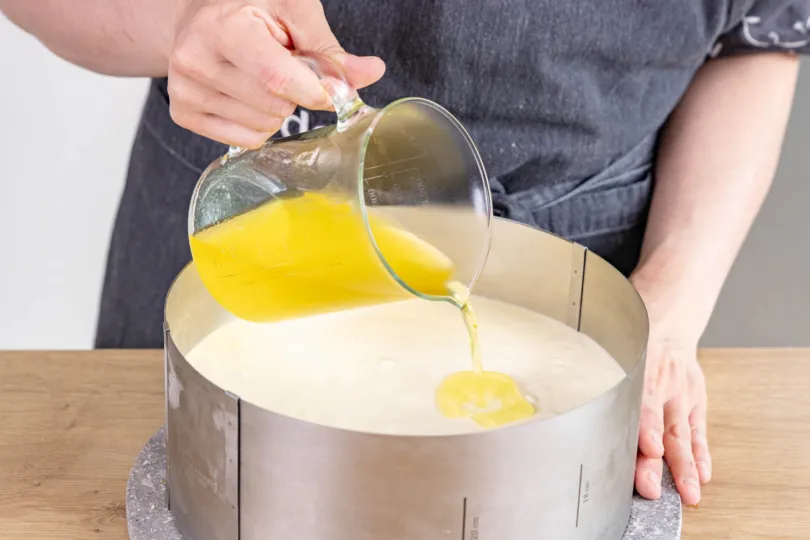 Abgekühlten Tortenguss gleichmäßig auf der Zitronen-Joghurt-Sahne-Torte verteilen