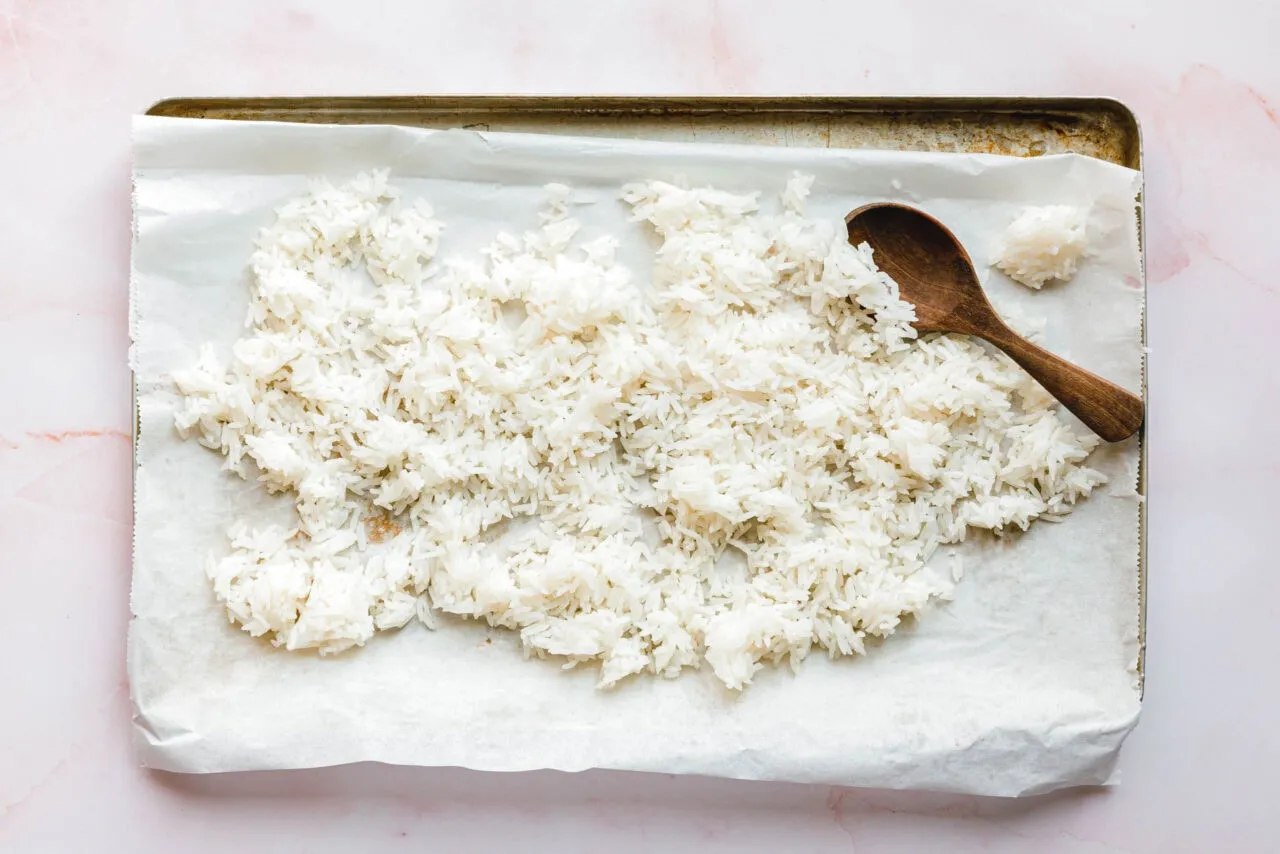 Abgekühlter, trockener Reis auf einem Backblech, bereit für die Zubereitung von veganen Reisgerichten.