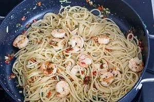 Abgetropfte Spaghetti mit Garnelen und der Soße vermengen.