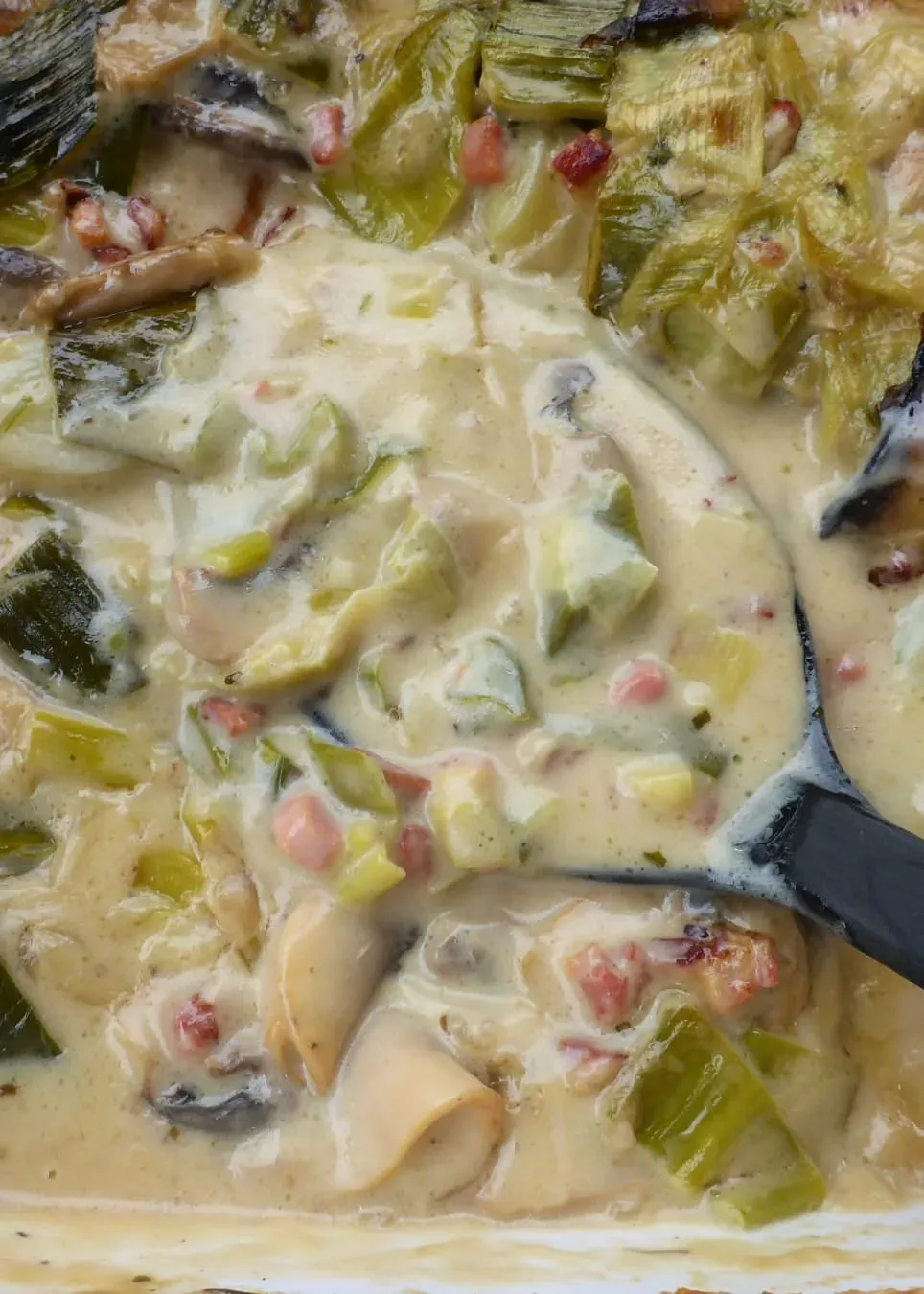 Alle frischen Zutaten für die Schnitzelpfanne auf einem Holztisch ausgebreitet: Schweinefilet, Pilze, Lauch, Speck, Sahne und Gewürze, bereit für die Zubereitung.