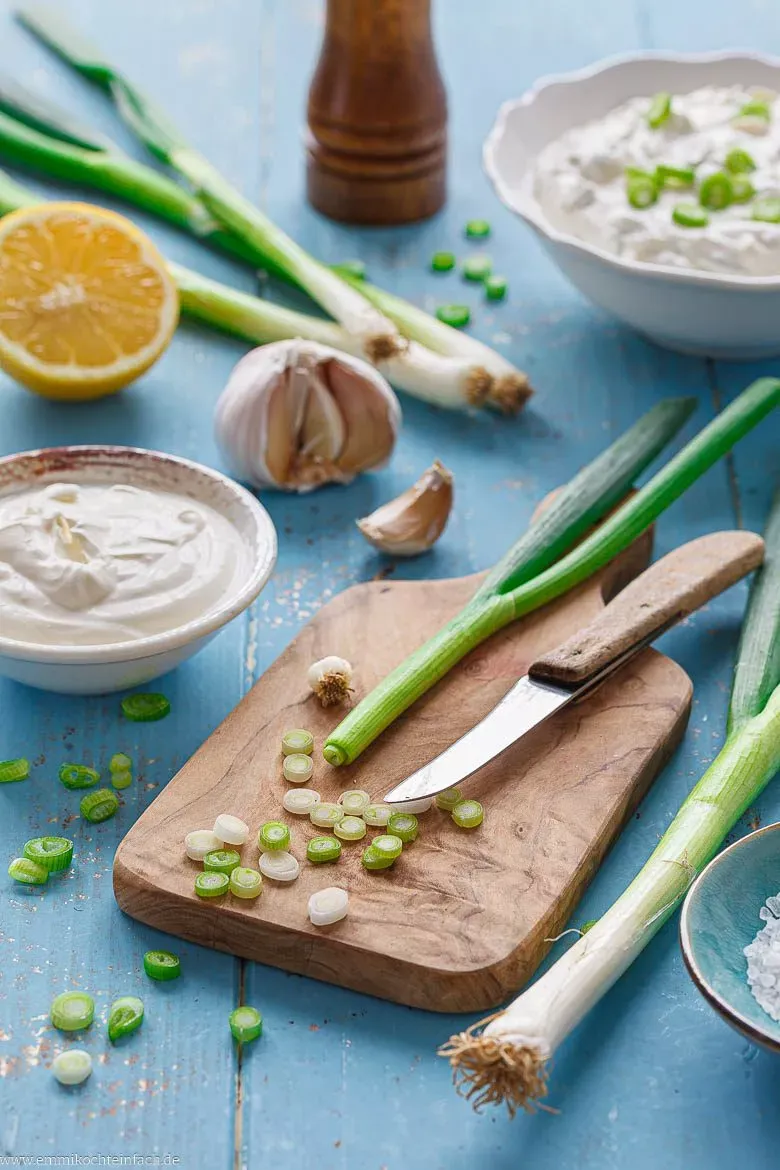 Alle frischen Zutaten für hausgemachte Sour Cream: Crème Fraîche, Quark, Frühlingszwiebeln, Knoblauch, Zitrone und Gewürze.