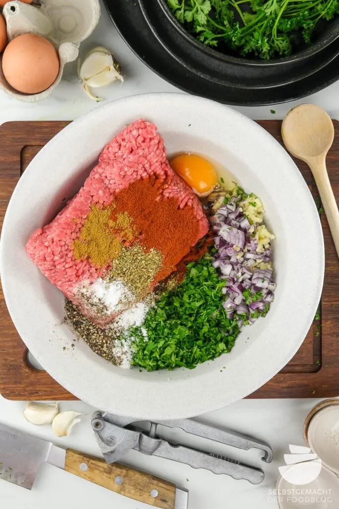 Alle frischen Zutaten übersichtlich arrangiert für das authentische köfte rezept, inklusive Hackfleisch und Gewürzen.