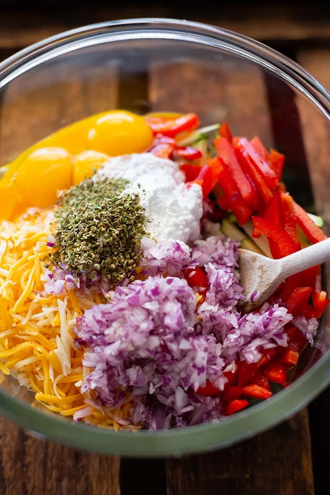 Alle kleingeschnittenen Zutaten für die herzhafte Gemüse-Quiche: Gemüse, Eier, Mehl, Zwiebel, Käse und Gewürze.