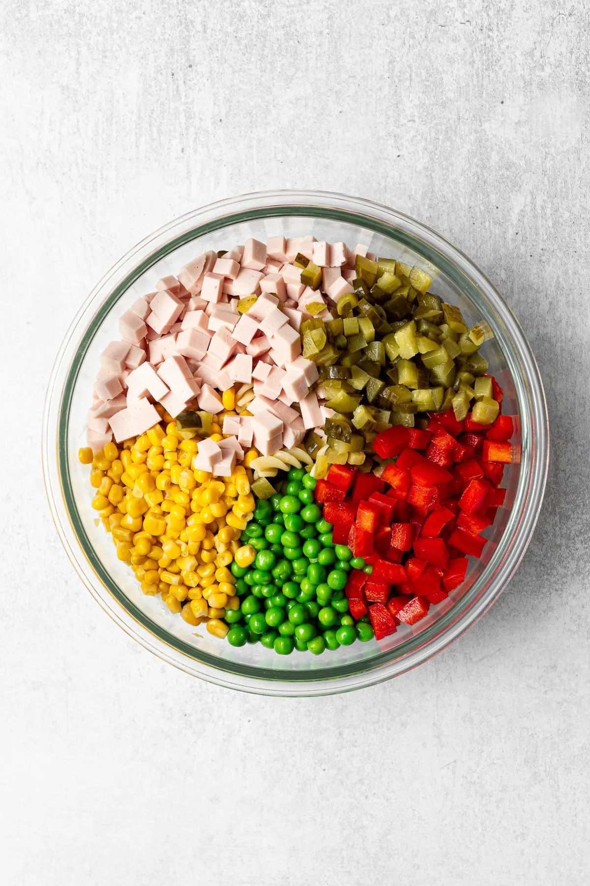 Alle Zutaten für deutschen Nudelsalat in einer großen Rührschüssel vor dem Mischen