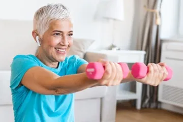 Ältere Frau benutzt Hanteln in ihrem Zuhause.