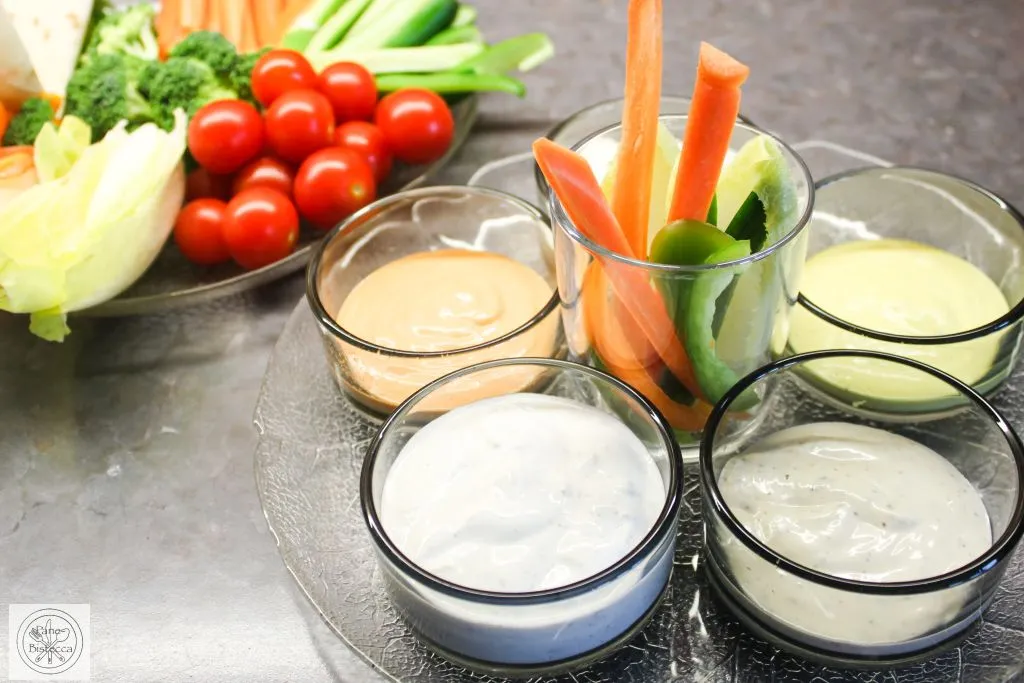 An angerichteter Platte mit Gemüsesticks und vier verschiedenen Dips