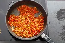 Andünsten von Gemüse und Paprikapulver in einer Pfanne für Djuvec Reis