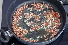 Angebratener Speck und Knoblauch in der Pfanne