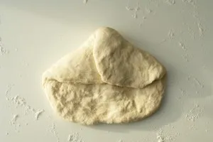 Anleitung zum Falten des Baguette-Teigs: Die ersten Schritte, wie der Teig von links und rechts eingeschlagen wird.