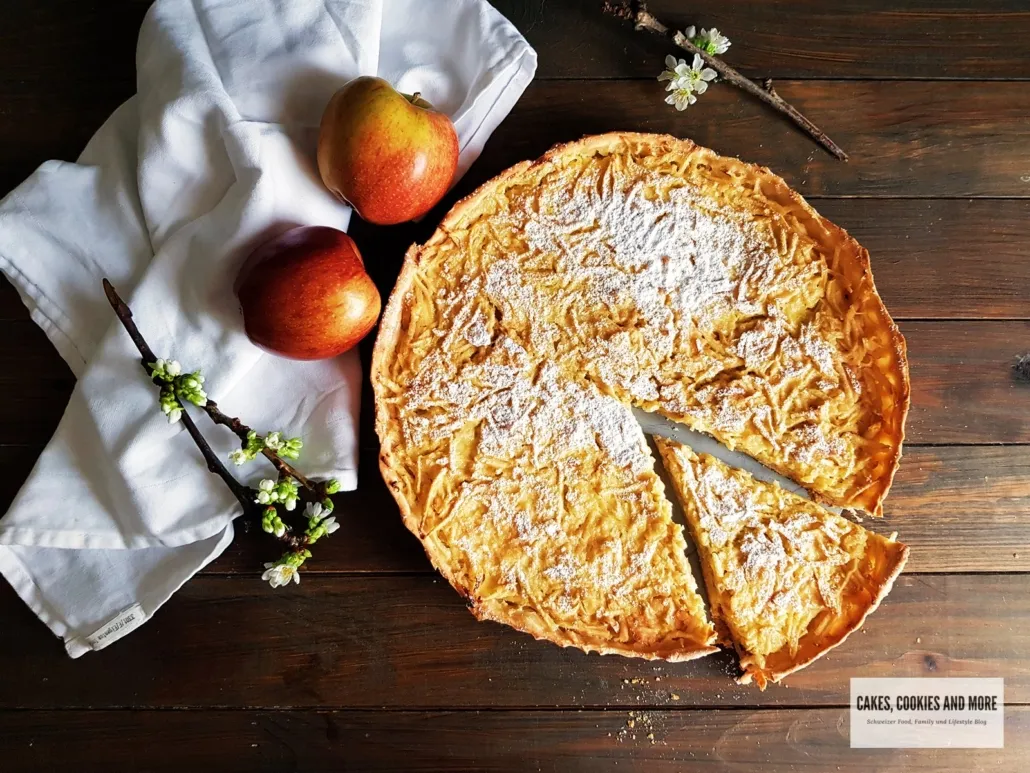 Anschnitt einer Apfelwähe, die saftige Apfelfüllung und den cremigen Guss zeigend.