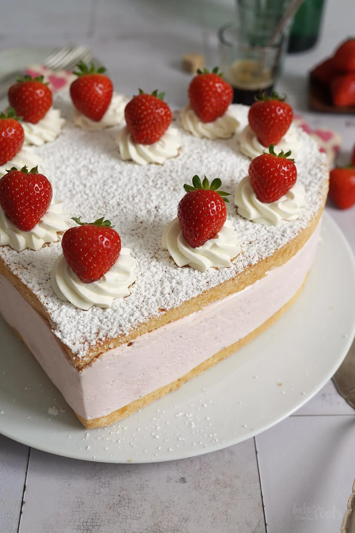 Anschnitt einer Erdbeer-Käsesahnetorte in Herzform mit cremiger Füllung