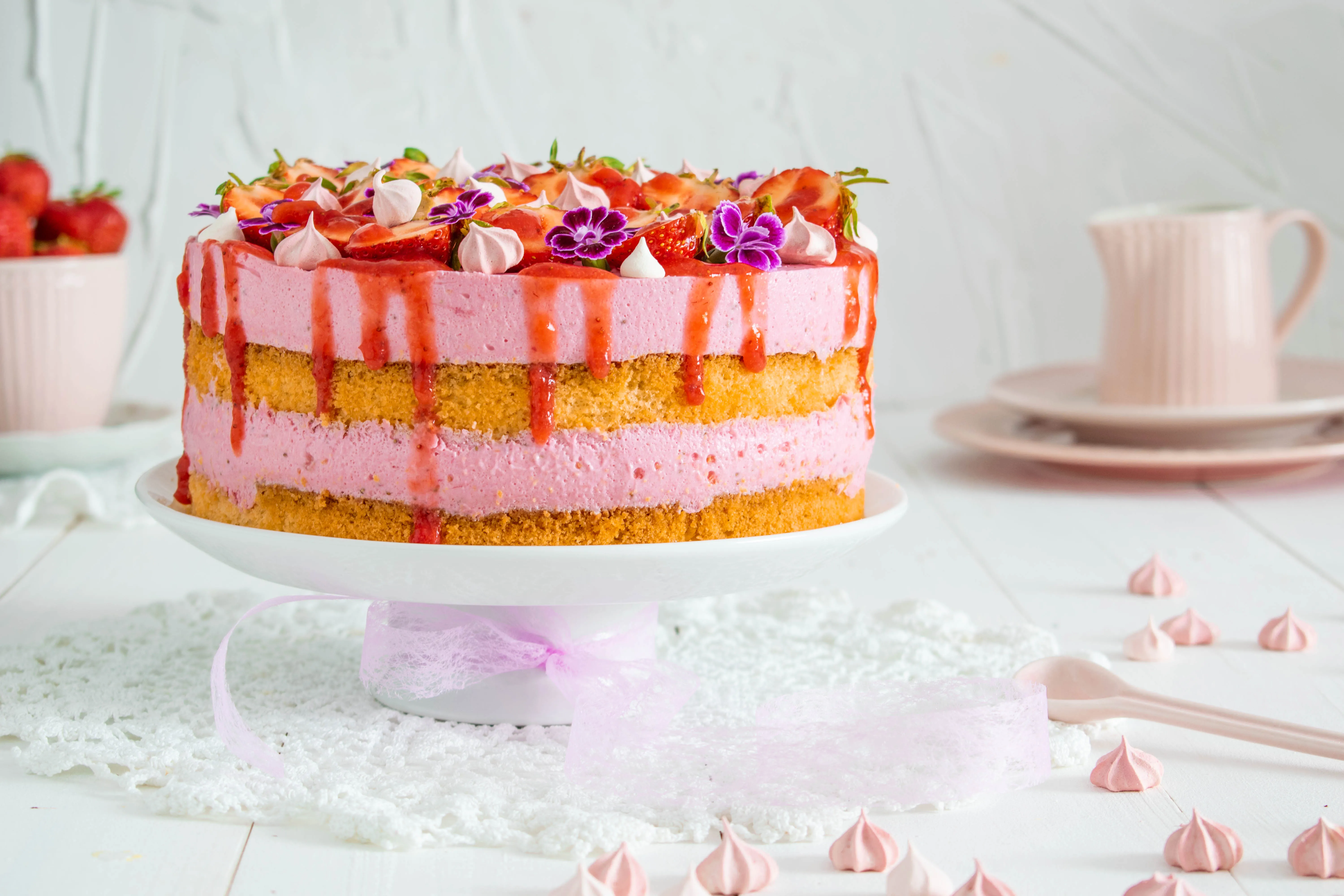 Anschnitt einer Erdbeersahnetorte, die Schichten aus Biskuit und cremiger Erdbeersahne zeigt, elegant dekoriert
