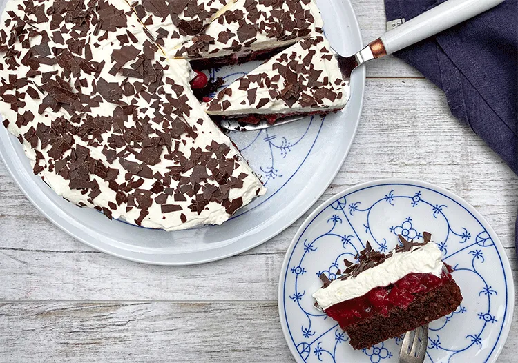 Anschnitt einer Kirsch Schoko Sahne Torte mit Schokoboden, Kirschfüllung und Sahneschicht