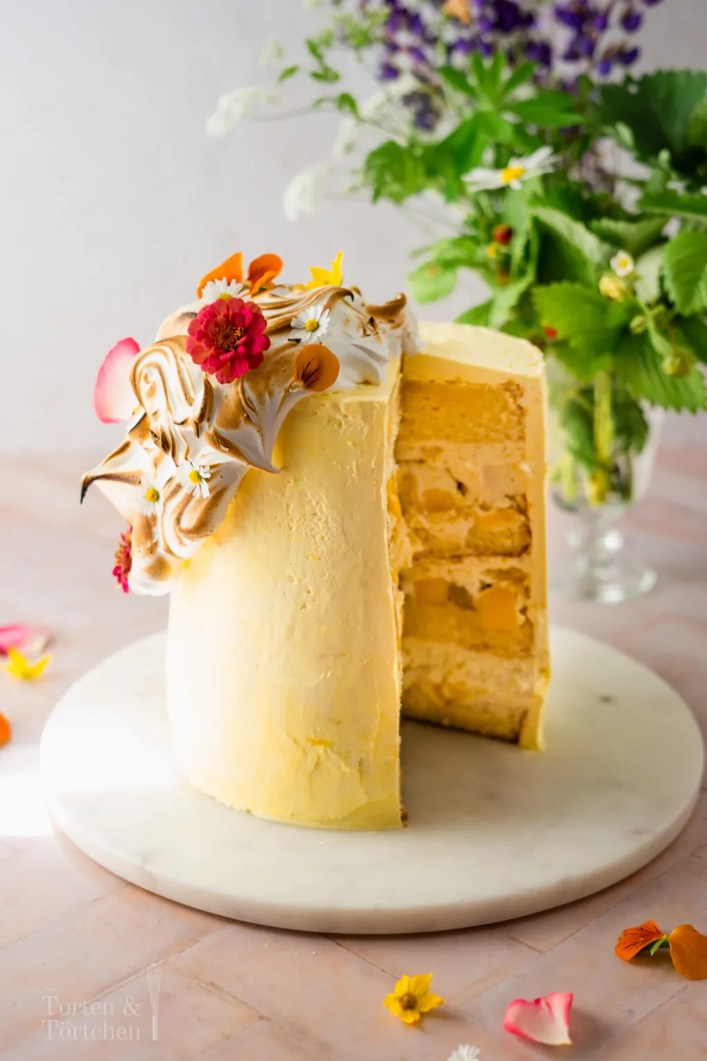 Anschnitt einer Mango Quark Sahne Torte, der die mehrschichtigen Vanilleböden, die cremige Quark-Sahne-Füllung und frische Mangostücke deutlich zeigt.