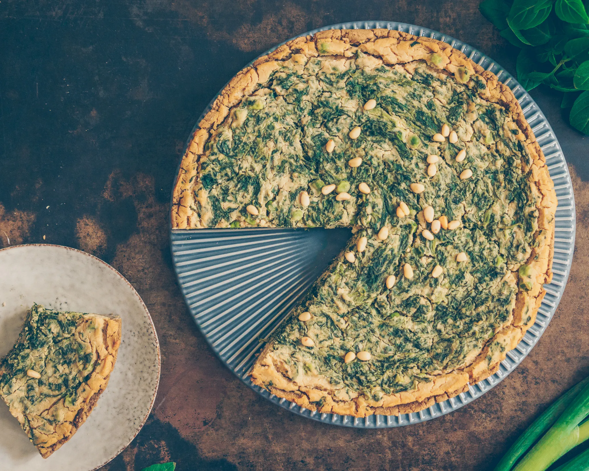 Anschnitt einer veganen Spinat Quiche mit frischen Kräutern