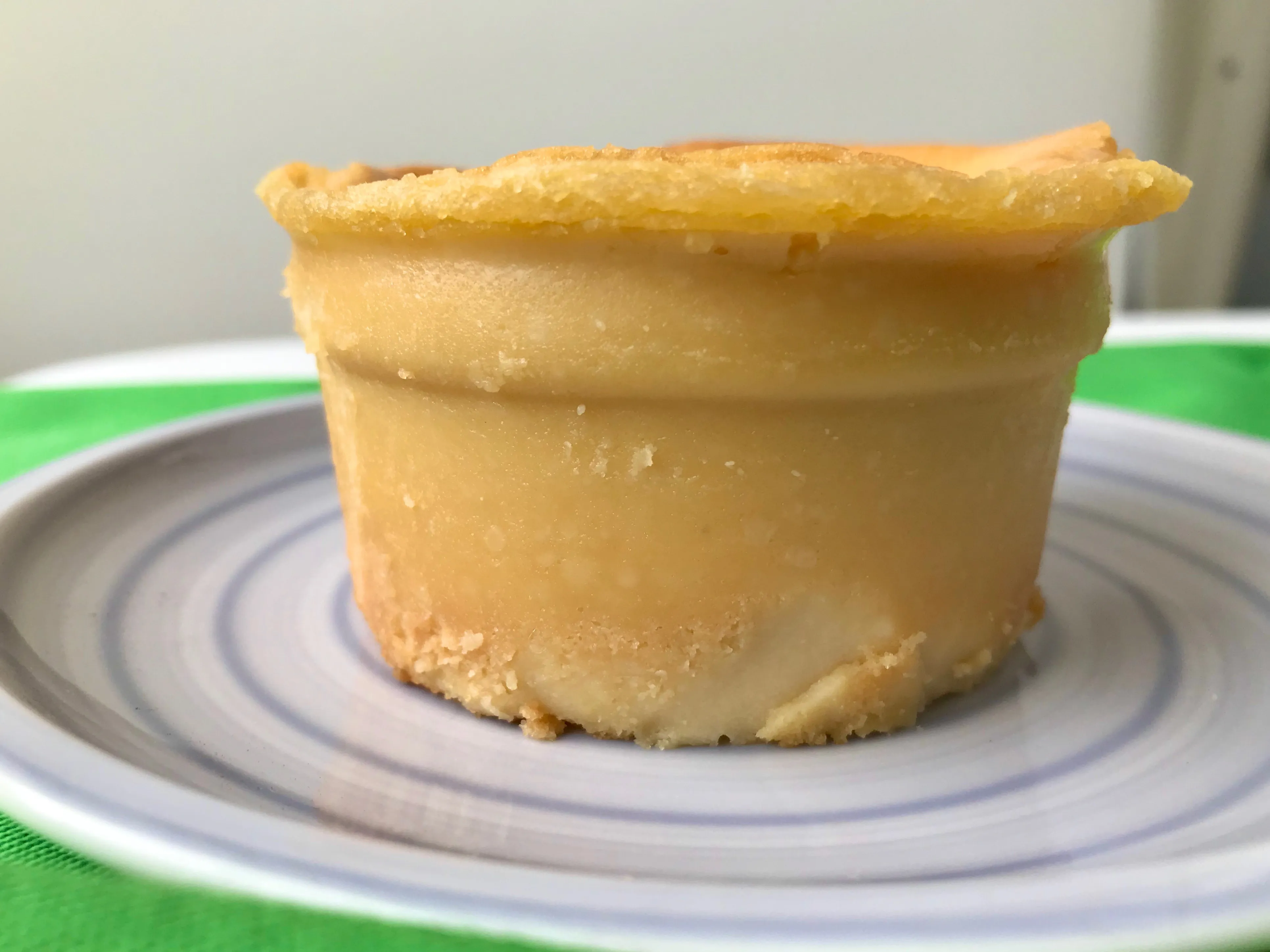 Ansprechend hellgelber veganer Käsekuchen, gebacken, in der Mitte leicht eingesunken mit glänzender Oberfläche