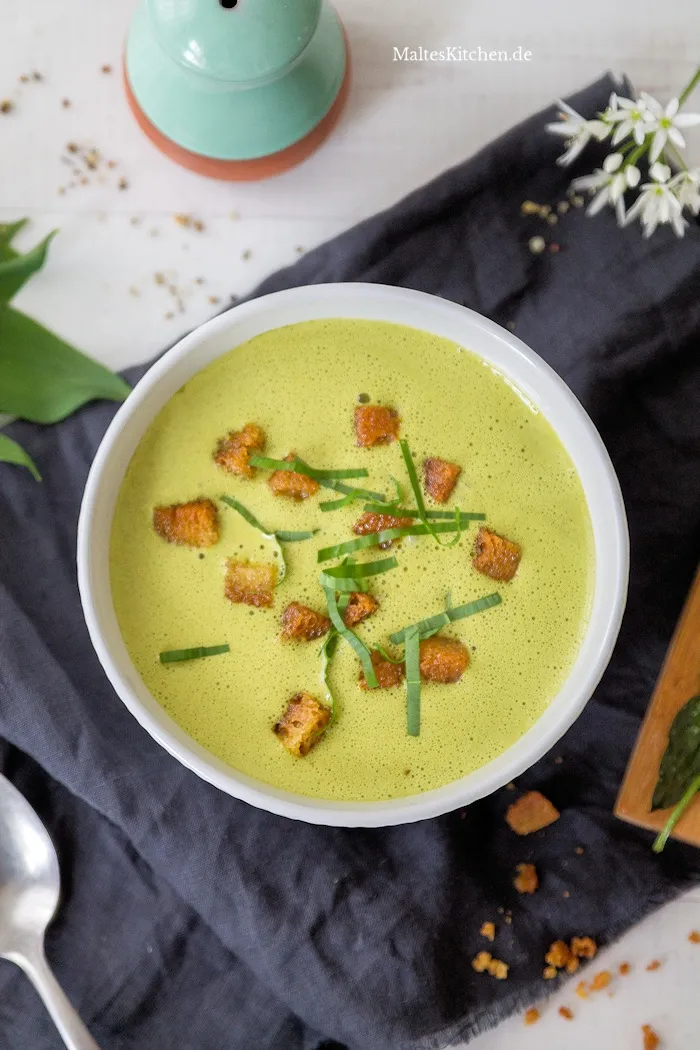 Ansprechende cremige Bärlauchsuppe, schaumig püriert und servierfertig in einer rustikalen Keramikschale, symbolisiert den deutschen Frühlingsgenuss.