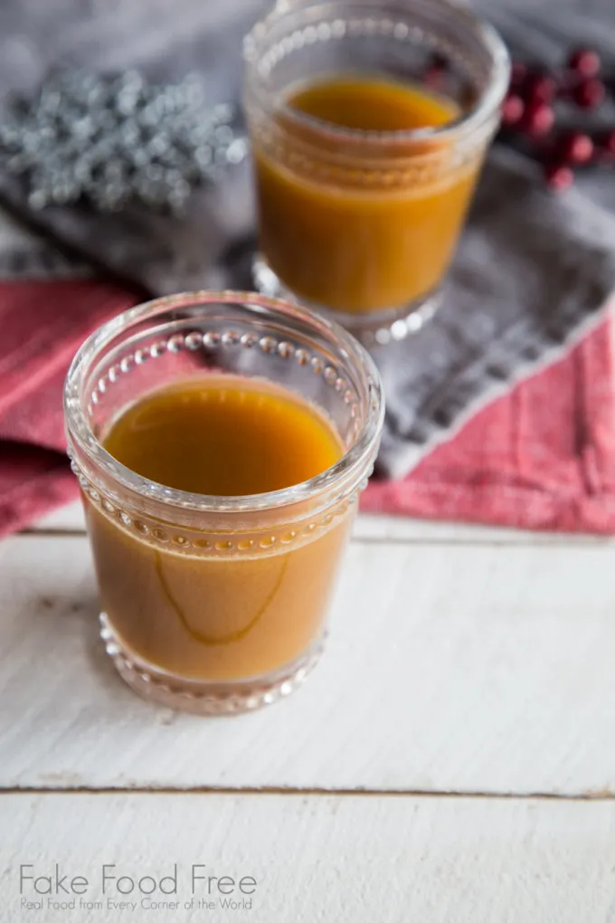 Apfelpunsch mit Rum in einem Glas, garniert mit Apfelscheiben und Zimtstangen, bereit zum Genießen.