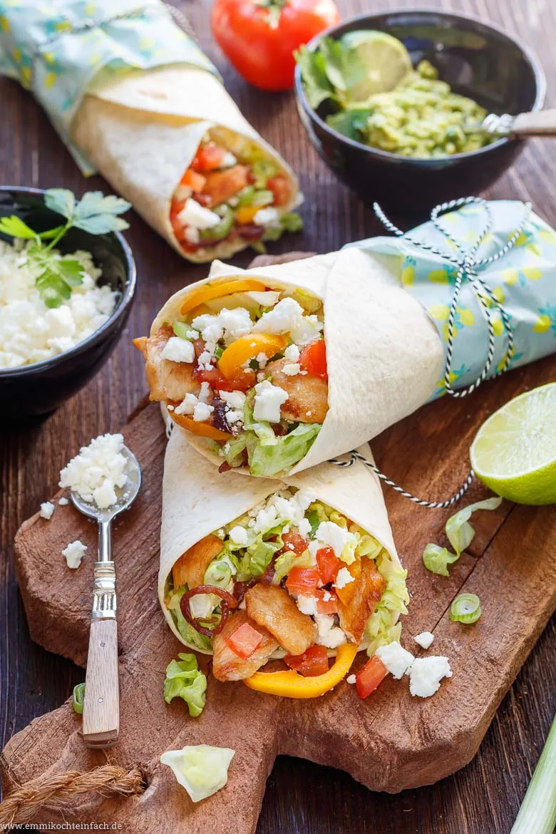 Appetitliche Hähnchen-Wraps, gefüllt mit Salat und Feta, auf Holzbrett serviert