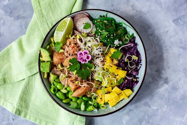 Appetitliche Lachs Poké Bowl, reich befüllt mit Sushi-Reis, Edamame, Mango und Wakame