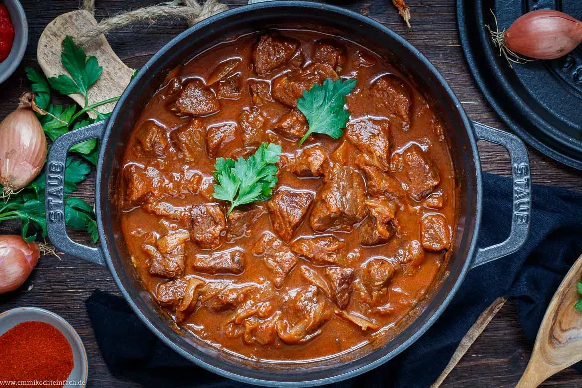 Appetitliches Rindergulasch mit dampfenden Kartoffelklößen, einer klassischen Beilage in der deutschen Küche.