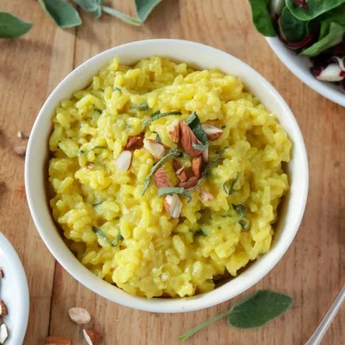 Appetitliches veganes Safranrisotto mit Salbeiblättern und gerösteten Mandeln, ein Genuss für die moderne Küche.