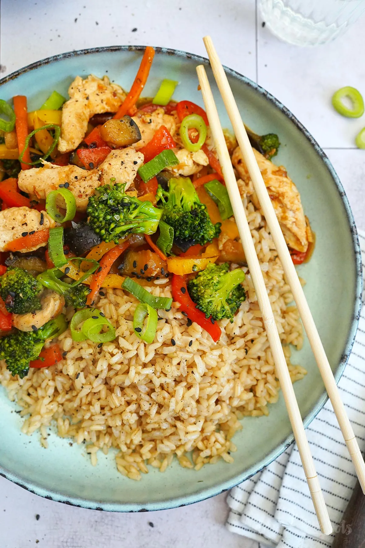 Appetitliches Wok Gericht mit Reis, Hähnchen und bunten Gemüsesorten in einer Schüssel angerichtet