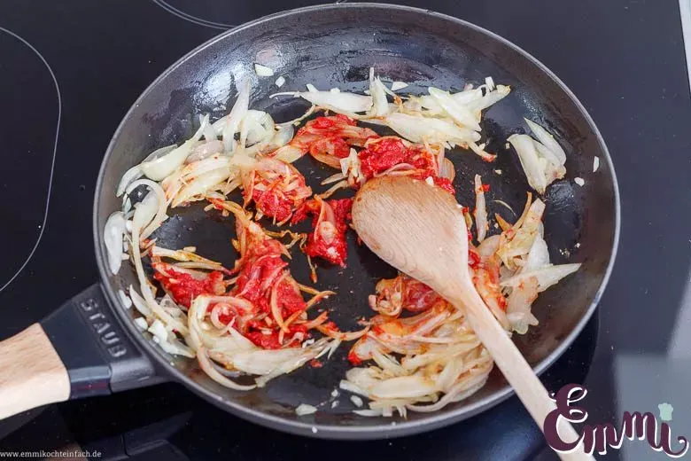 Aromatische Tomaten-Schalotten-Masse als Grundlage für das Zucchini-Aubergine-Rezept, in einer Pfanne.