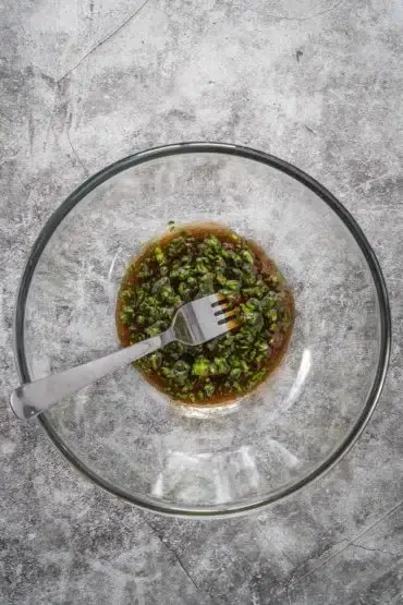 Aromatisches Salatdressing mit Olivenöl, Balsamico und frischen Kräutern für den toskanischen Brotsalat verrühren