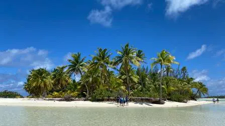 Atemberaubender Blick auf das Aitutaki Atoll der Cookinseln in der Südsee, mit einer Insel im Vordergrund und einer türkisblauen Lagune.