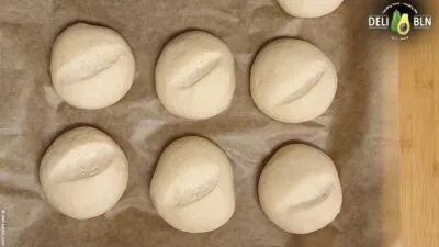 Aufgegangene und eingeschnittene Brötchen vor dem Backen mit Wasser besprüht