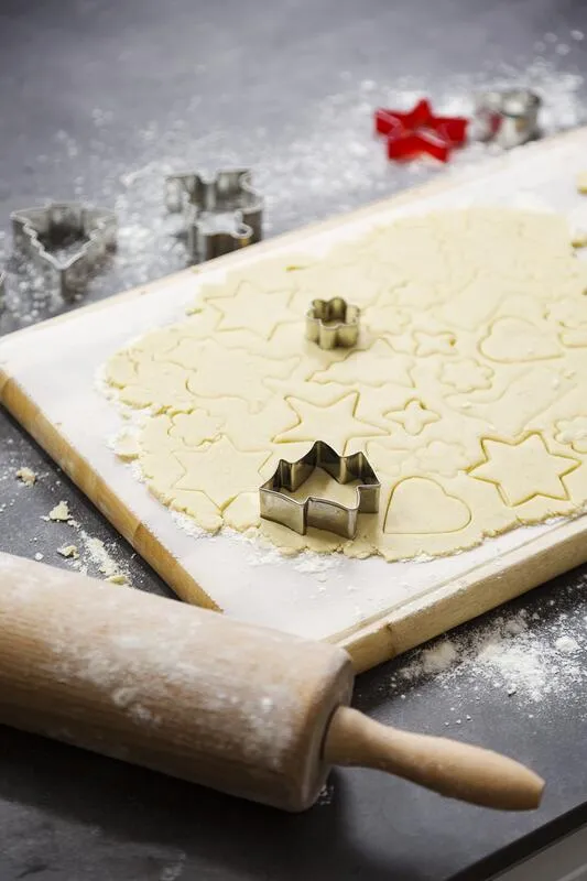 Ausgerollter Mürbeteig mit Ausstechern auf Holzbrett