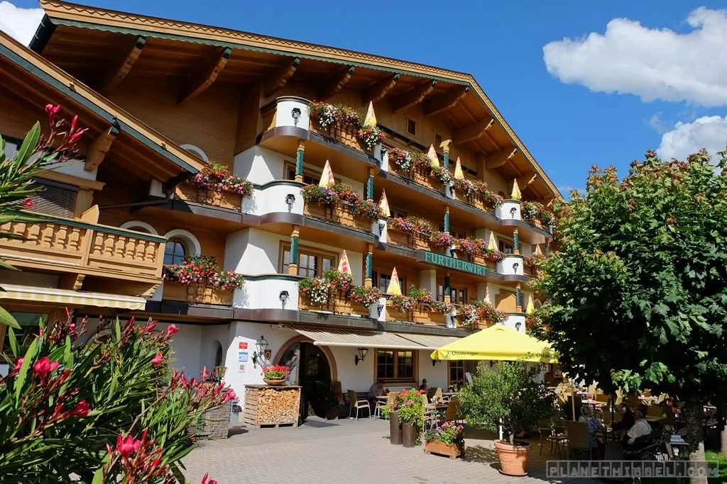 Außenansicht des Familienhotels Furtherwirt in Tirol mit blühenden Blumenkästen an den Fenstern
