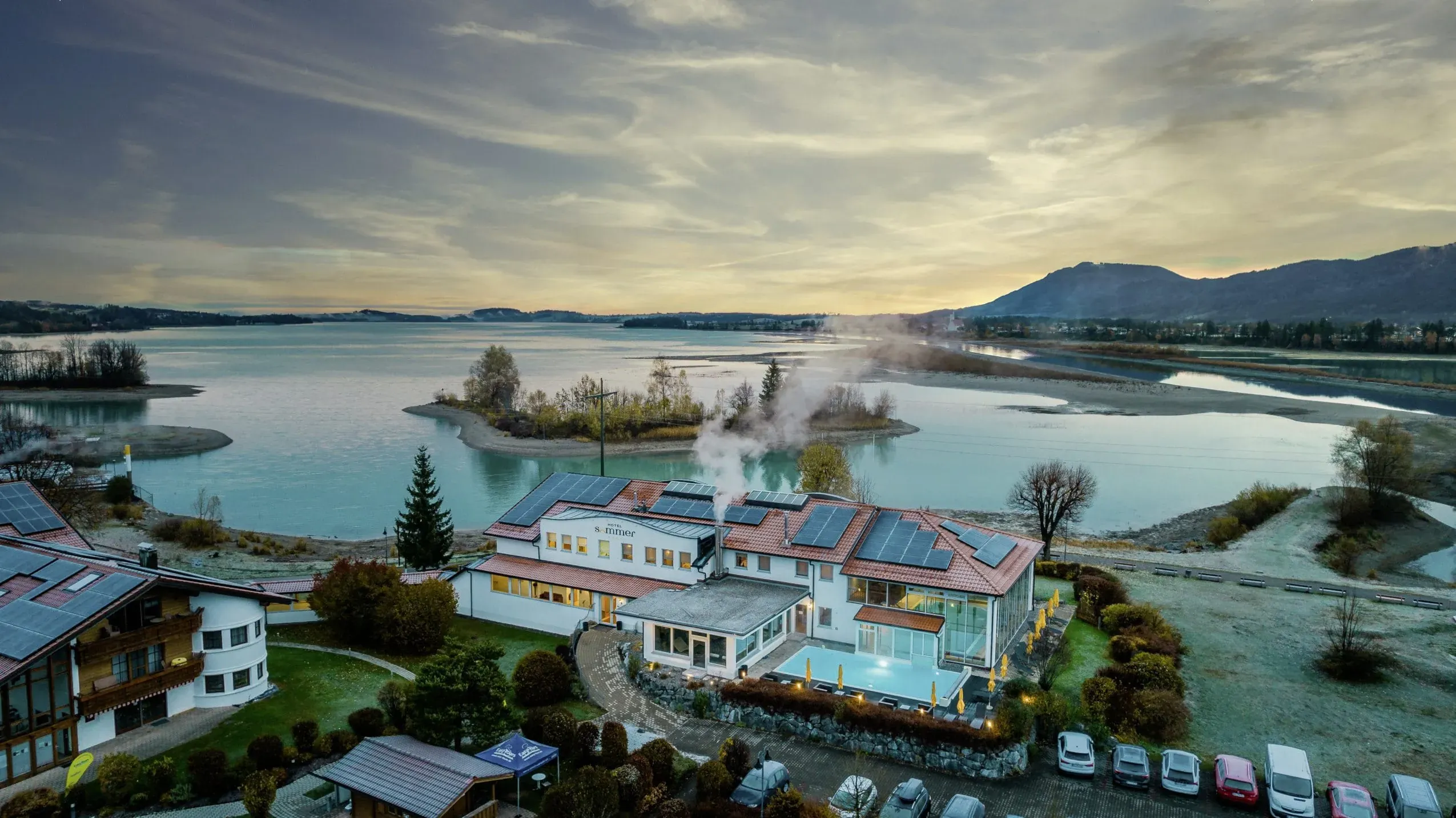 Außenansicht des Hotel Sommer in Füssen mit malerischem Blick auf den Forggensee und die majestätischen Alpen – ein perfektes Hotel mit Hund am See.