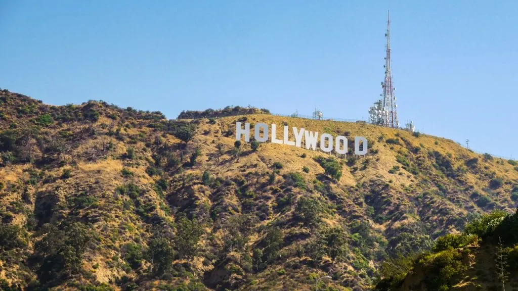 Aussicht auf das Hollywood Sign von einem Hügel aus, umgeben von Bäumen und Häusern