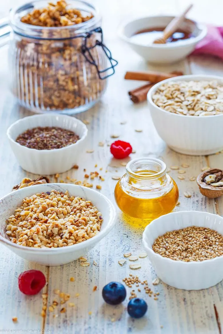 Auswahl an frischen Granola Zutaten: Haferflocken, Nüsse, Leinsamen, Honig und Zimt bereit zur Zubereitung.