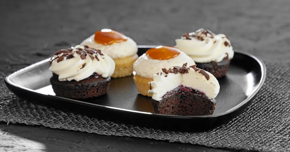 Auswahl an Pfalzgraf Torten und Kuchen: Neuheiten 2023, darunter Schwarzwälder Kirsch Cupcake und veganer Schoko-Birnen-Kuchen