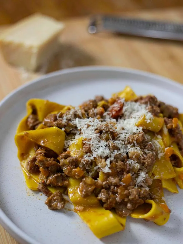 Authentisches Ragù alla Bolognese mit frisch geriebenem Parmesan auf Pappardelle