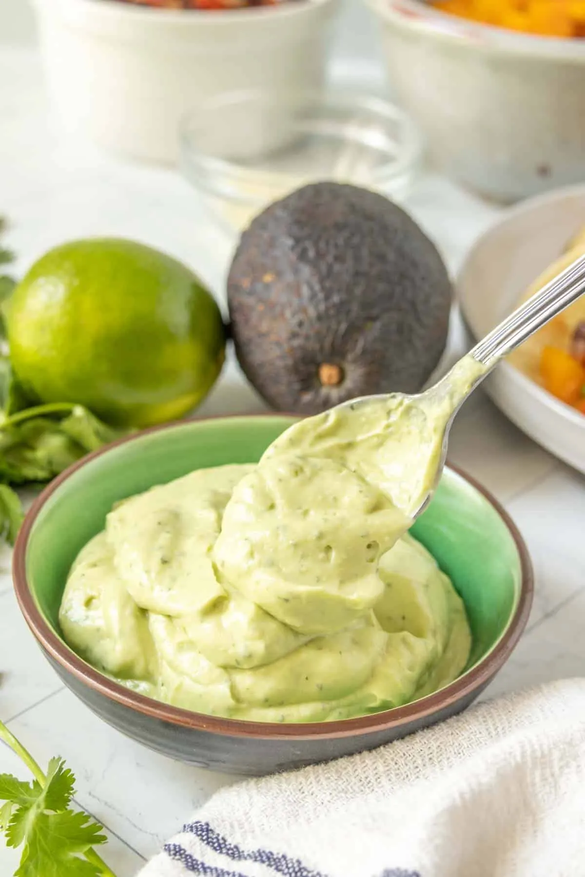 Avocado Creme in einer Schale mit Limetten und Koriander.
