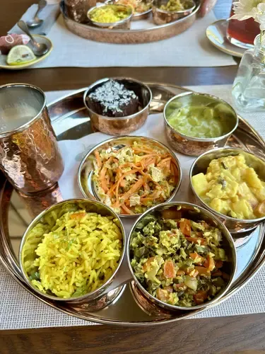 Ayurvedisches Mittagessen im Thali-Stil mit Currys, Reis, Lassi und Brownie