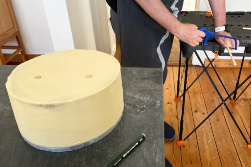 Bäckerin sägt einen Tortendübel aus Holz zu, zwei weitere sind bereits in der Torte