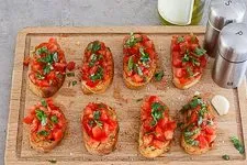 Belegte Bruschetta Scheiben mit Tomaten, Basilikum und Gewürzen