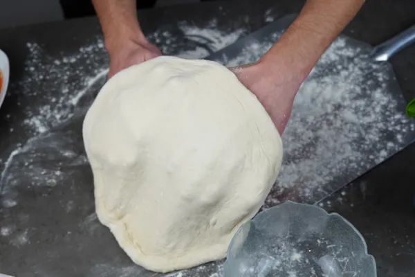 Bemehlten Pizzateig vorsichtig auf die Pizzaschaufel heben