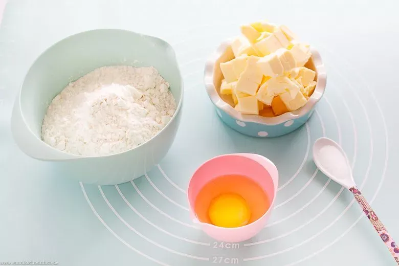 Bereitgestellte Zutaten für Quiche Teig: Mehl, gewürfelte kalte Butter, Ei, Salz.
