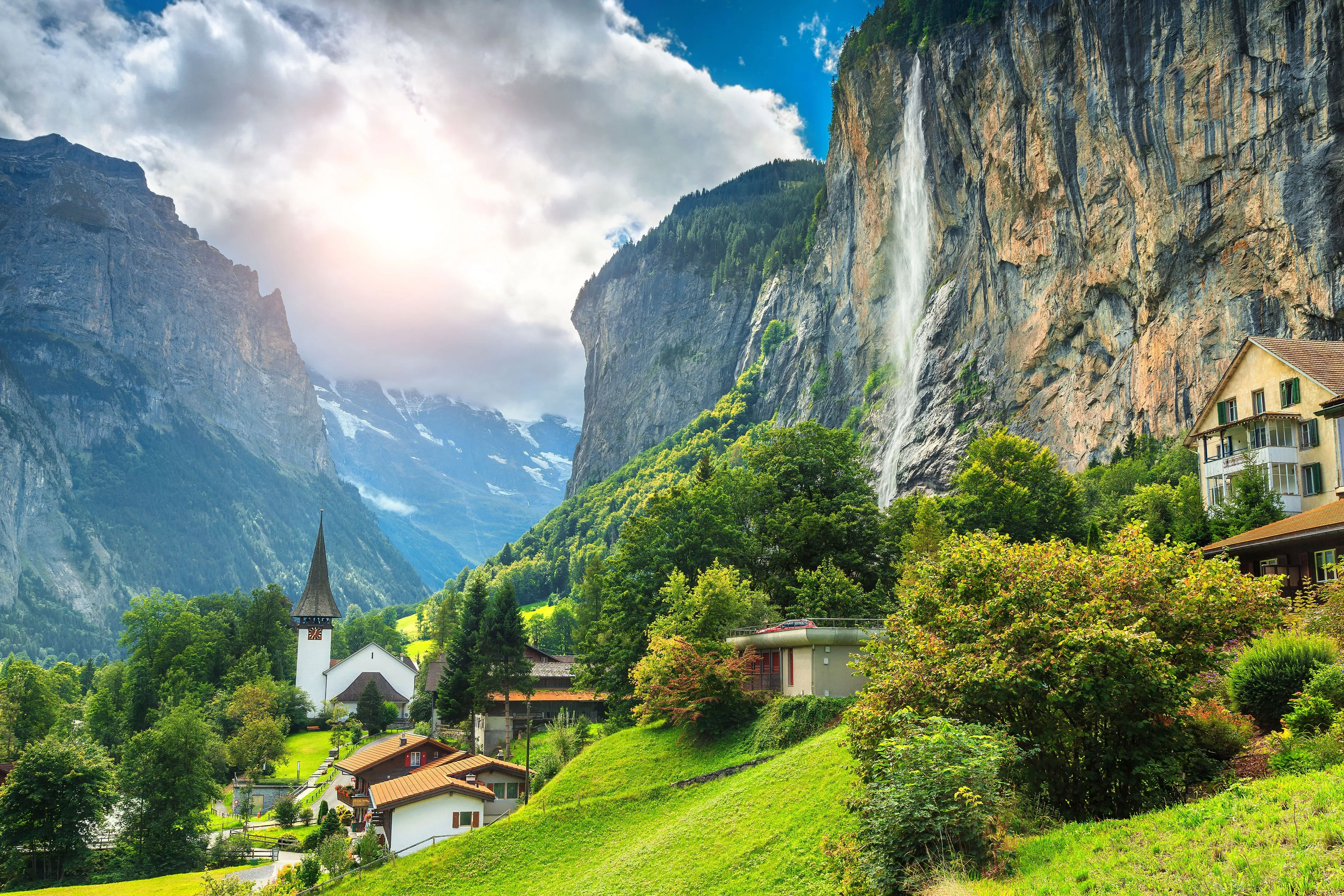 Blick auf den Ort Lauterbrunnen in der Schweiz mit seinen kleinen Häusern, grünen Wiesen und schneebedeckten Berggipfeln