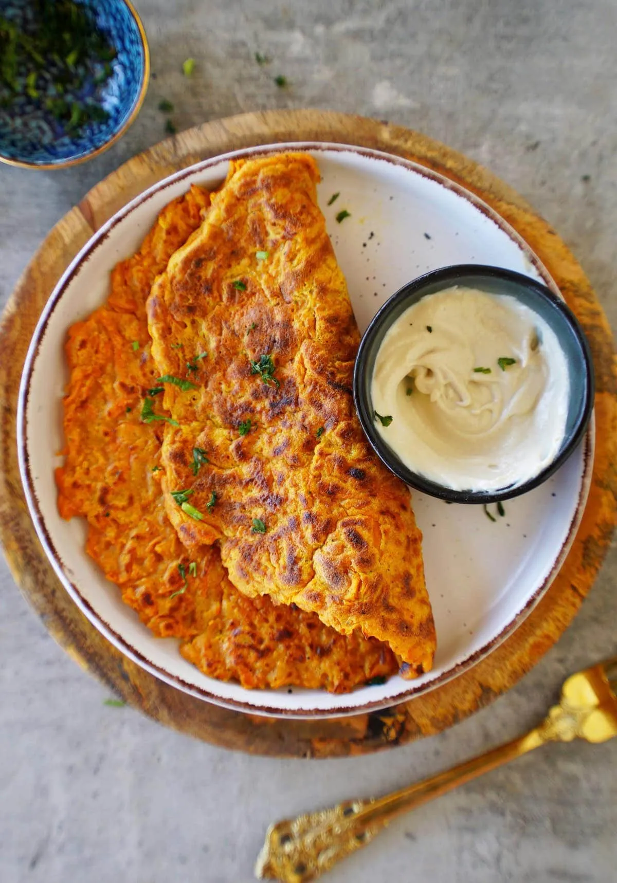Blick von oben auf ein rundes Karotten-Omelett mit Kräuterdekoration auf einem Teller