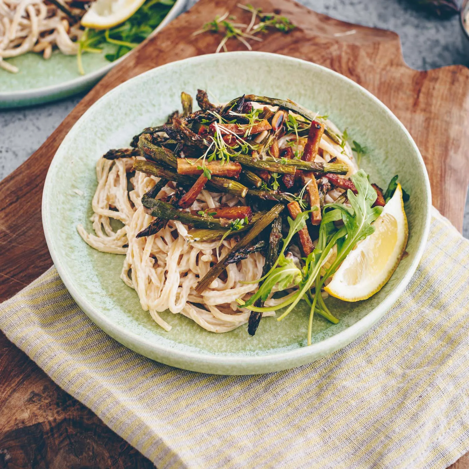Blick von oben auf eine dampfende Portion veganer Frühlingspasta mit gebratenem Spargel und Tofu