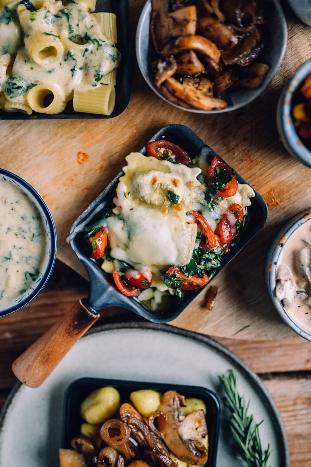 Blubberndes Raclette-Pfännchen gefüllt mit Pasta und reichlich geschmolzenem Käse